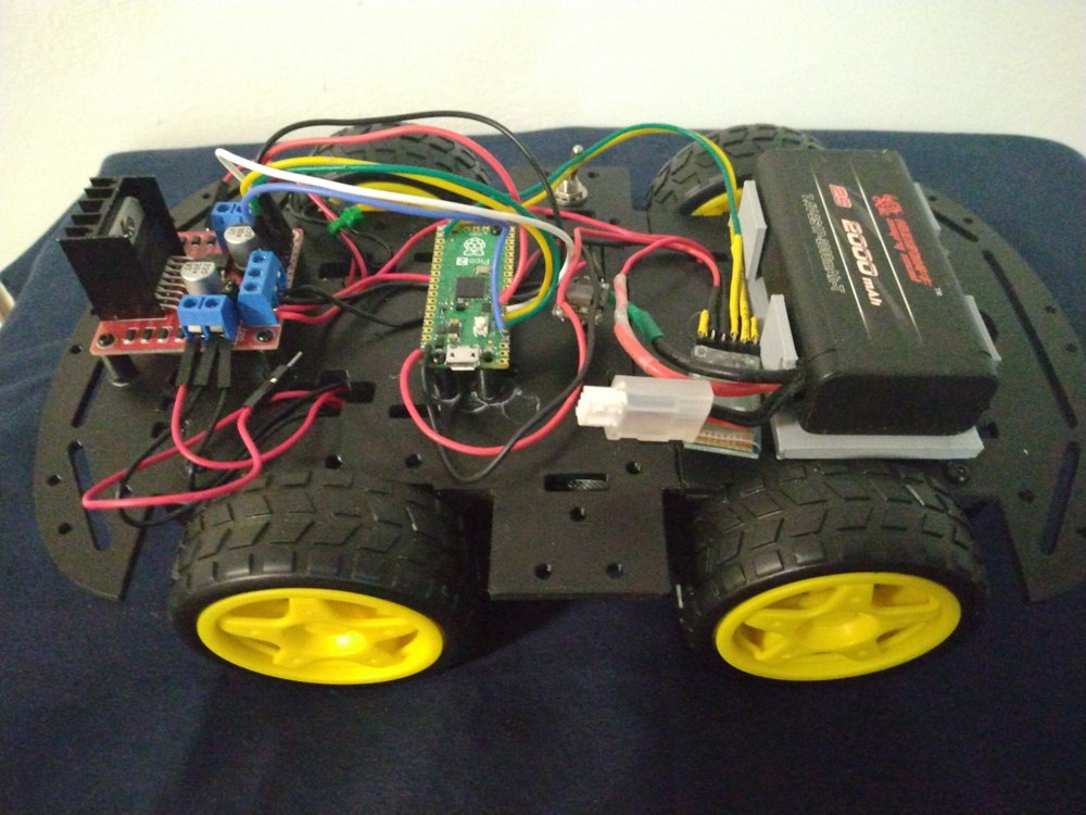 Pico 2 car with four yellow wheels, a black chassis, L298N motor driver, Pico board, battery pack, and wiring.