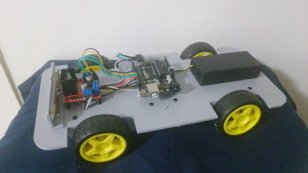 Earlier Wi-Fi car setup supplied by George, showing a gray chassis, four yellow wheels, L298N motor driver, an ELEGOO UNO R3 board, battery enclosure, and wiring.